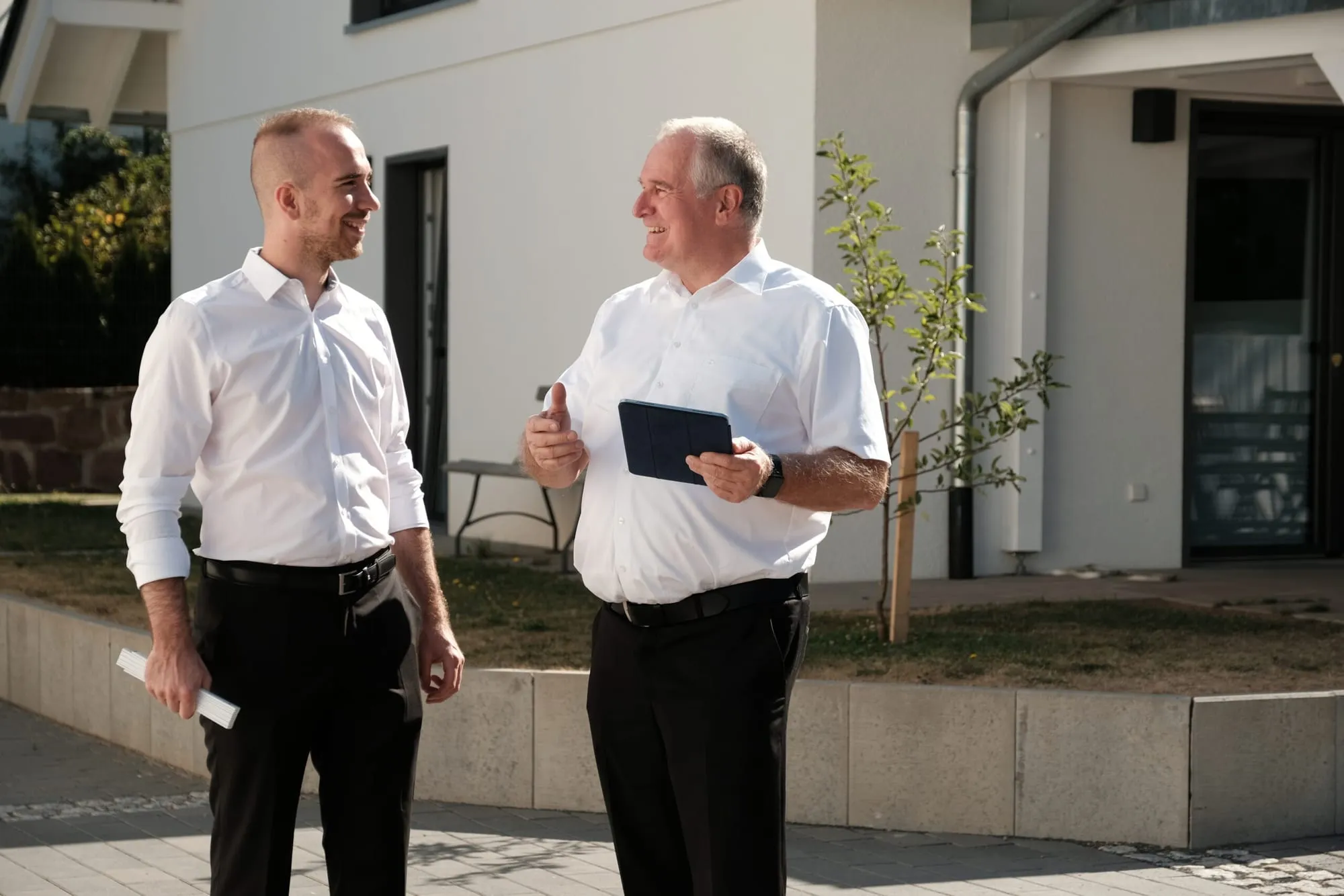 Zwei Mitarbeiter im Gespräch vor einem Neubau